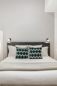 1 cama con almohadas y pared blanca en Homs Boutique Apartment, en Roma