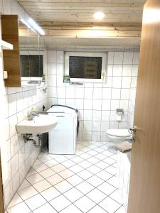 un bagno piastrellato bianco con lavandino e servizi igienici di Ferienwohnung Dornfelder a Kitzingen