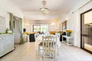 uma sala de jantar com uma mesa branca e cadeiras em Villa Palmeiras - Serene Private Villa em Albufeira