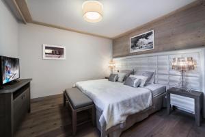 1 dormitorio con 1 cama grande y TV en Résidence Carre Blanc - 3 Pièces pour 6 Personnes 474, en Courchevel