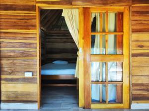 Cama pequeña en habitación de madera con puerta en Villa Esperanza, en Palomino