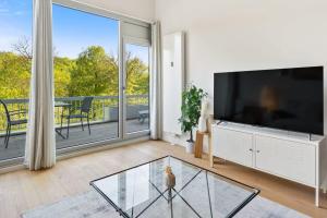 a living room with a large television and a balcony at Elegant 1BR Apt, Balcony, Pool, Central Location in Luxembourg