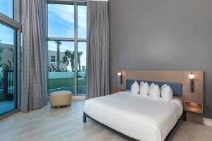 a bedroom with a white bed and a large window at Max Beach Resort in Daytona Beach