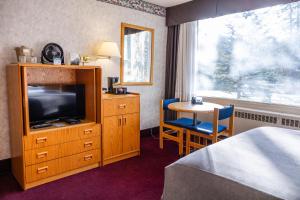 Habitación de hotel con cama, TV y mesa. en Bow View Lodge, en Banff
