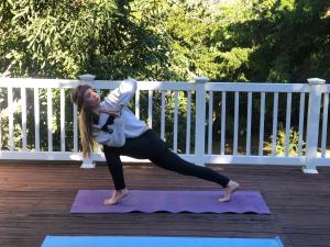 a woman doing a yoga pose on a yoga mat at Kidds beach house in Kiddʼs Beach