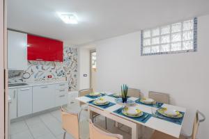 uma cozinha com uma mesa com cadeiras e uma cozinha com armários vermelhos em [Amalfi Coast]Elegant house in Penisola Sorrentina em Vico Equense