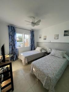 a bedroom with two beds and a ceiling fan at Tramontana Villa in Cala'n Porter