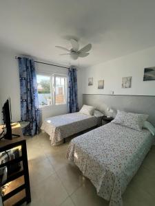 a bedroom with two beds and a ceiling fan at Tramontana Villa in Cala en Porter