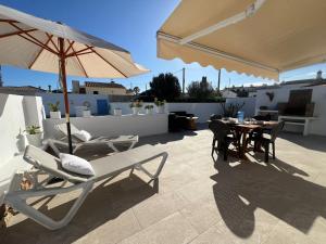 a patio with chairs and an umbrella and a table at Tramontana Villa in Cala en Porter