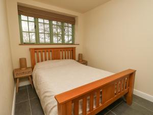 a bedroom with a wooden bed and a window at Coach House in Denbigh
