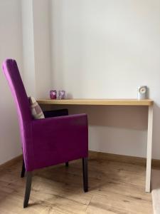 una silla púrpura sentada frente a un escritorio en Sophie Apartment, en Poznan