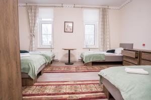 Cette chambre comprend 3 lits, une table et 2 fenêtres. dans l'établissement Mazurek - pokoje do wynajęcia, à Duszniki-Zdrój