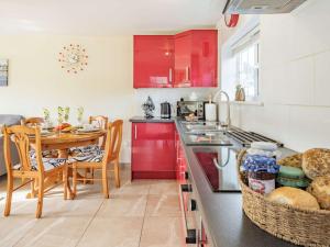 cocina con armarios rojos y mesa de comedor en 2 Bed in Bude 86920, en Kilkhampton