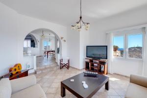 a living room with a couch and a tv and a table at Villa la vue in Ano Syros