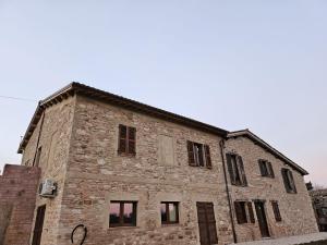 um velho edifício de tijolos com janelas do lado em Agriturismo Il Raggio di sole di Orpello em Camerino