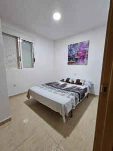 een slaapkamer met een bed met een schilderij aan de muur bij habitacion en piso compartido cerca de playa in Xilxes