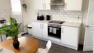 a kitchen with white cabinets and a wooden table at Herbert - Duplex Relocations in Mexborough