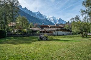 una casa in un campo con montagne sullo sfondo di Résidence Perseverance - Chalets pour 12 Personnes 054 a Chamonix-Mont-Blanc