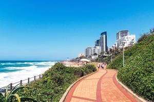 einen Backsteinweg neben dem Strand mit Gebäuden in der Unterkunft North Breeze Retreats in Durban