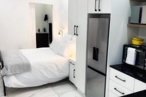 a small white bedroom with a bed and a microwave at North Breeze Retreats in Durban