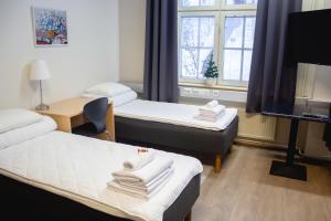 a room with two beds and a desk and a television at Hostel Hermanni in Kuopio