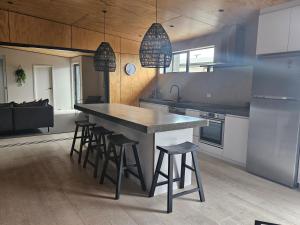a kitchen with a large counter with stools in it at The Totara Bach in Twizel