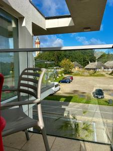 a chair on a balcony looking out at a parking lot at Apartament Klifowy Raj SPA & Restaurant by Stayly in Niechorze
