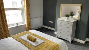 een slaapkamer met een bed, een spiegel en een dressoir bij Herbert - Duplex Relocations in Mexborough