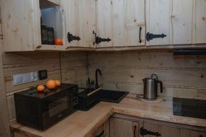 una cocina con armarios de madera y una barra con naranjas en Domek pod lasem-Orawskie Ranczo, en Harkabuz