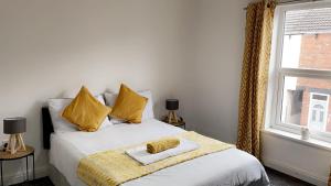 a bedroom with a bed with yellow pillows and a window at Herbert - Duplex Relocations in Mexborough