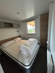 a large bed in a small room with a window at Mobil'home - Camping **** Les Charmettes in Les Mathes