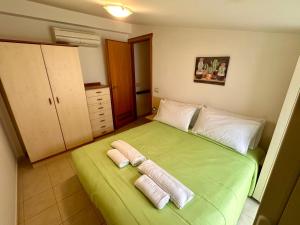 um quarto com uma cama verde e toalhas em Sperlonga Paradise Apartment Complex em Sperlonga