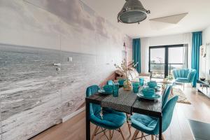 a dining room with a table and blue chairs at Seaview Plaza in Dziwnów