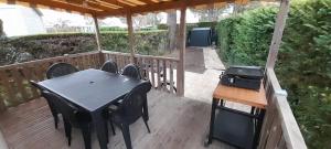 eine Terrasse mit einem Tisch, Stühlen und einem Grill in der Unterkunft Mobil'home - Camping **** Les Charmettes in Les Mathes