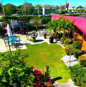 um jardim com um parque com cadeiras e um guarda-sol rosa em Lantern Inn & Suites - Sarasota em Sarasota