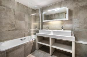 a bathroom with two sinks and a mirror and a tub at Résidence Carre Blanc - 5 Pièces pour 8 Personnes 384 in Courchevel