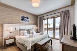 a bedroom with a large bed and a balcony at Résidence Carre Blanc - 4 Pièces pour 6 Personnes 404 in Courchevel