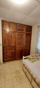 a bedroom with a bed and wooden cabinets at Tu casa lejos de tu casa in David
