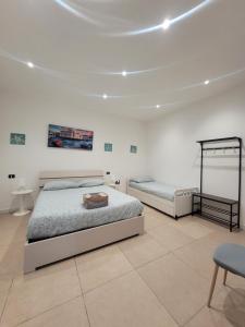 a white bedroom with two beds and a chair at House del Levante in Bari