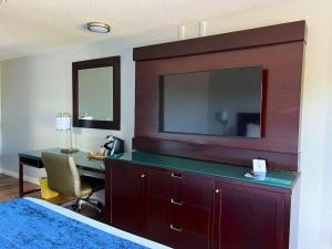1 dormitorio con escritorio, TV y cama en Lantern Inn & Suites - Sarasota en Sarasota