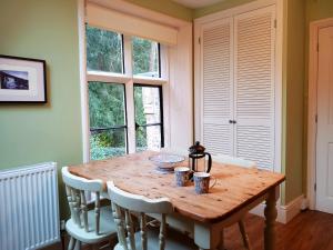 een houten tafel in een kamer met stoelen en ramen bij Haslington House in Malvern Wells
