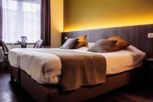 a large bed in a hotel room with a table at Hotel des Postes in Houffalize