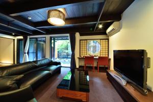 a living room with a black leather couch and a television at Takeya Kitano Honkan in Kyoto