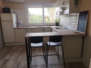a kitchen with a counter and two chairs at a table at Suite Huelva garden in Aljaraque