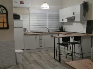 cocina con armarios blancos, mesa y sillas en Suite Huelva garden, en Aljaraque