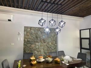 a dining room with a table and a stone wall at Camotes Resthouse in Camotes Islands