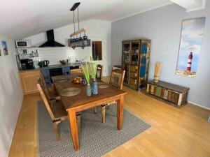 a dining room with a wooden table and a kitchen at discovAIR Graal-Müritz -Villa Victoria- Strandnah mit Netflix in Graal-Müritz +22 photos