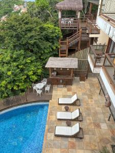 a swimming pool with chairs and a table next to a building at Pousada La Belle Maison Brigitte Bardot in Búzios