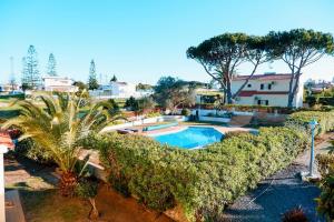 uitzicht op een zwembad met bomen en struiken bij Villa Miracampo - Elegant Secret in Albufeira