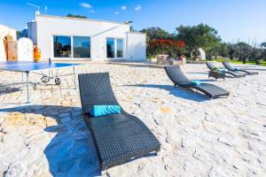 a patio with chairs and a table and a house at Villa Trullo Mammazia by Villa Plus in Carovigno